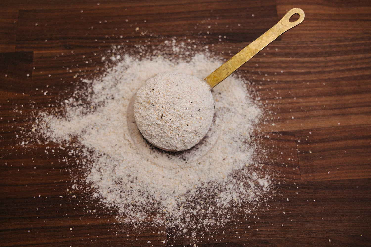 A quarter cup of seasoned flour measured out on a wooded board.